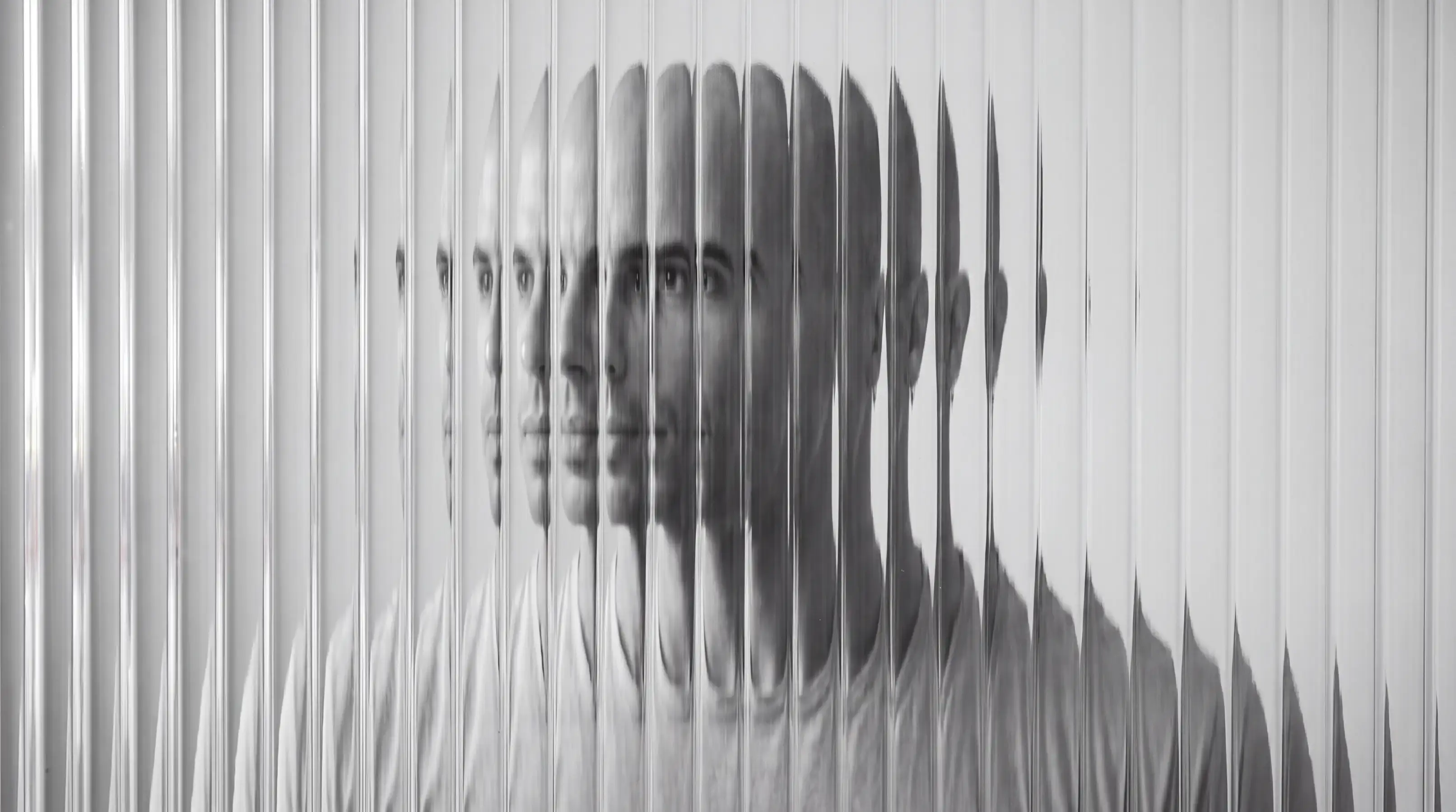 Black-and-white portrait of Serkan Ferah behind ribbed glass, his face split into repeating vertical slices